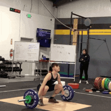 a man squatting down holding a barbell with kiloflex on it