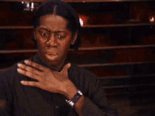 a woman is covering her mouth with her hand and making a face .