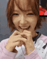 a close up of a woman making a heart with her hands .