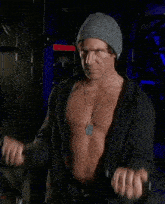a shirtless man wearing a beanie and a necklace is lifting a barbell in a gym .