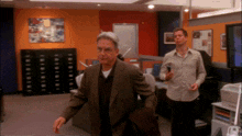 a man in a suit and a man in a white shirt are in an office