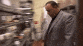 a man in a suit and tie is standing in a kitchen looking down at something .