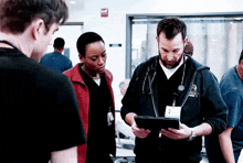 a group of doctors are looking at a tablet together in a hospital room .