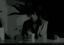 a black and white photo of a man holding a cup
