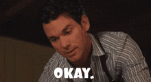 a man in a striped shirt says " okay " in white letters