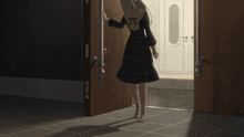 a woman in a plaid dress stands in a doorway