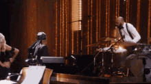 a man playing drums while a woman stands behind him