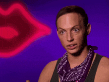a man wearing a purple bandana is sitting in front of a neon lip