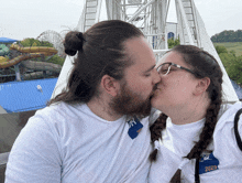a man and woman are kissing in front of a ferris wheel