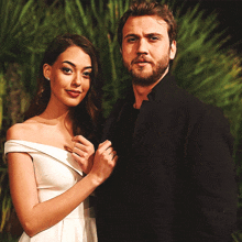 a man with a beard and a woman in a white dress pose for a photo