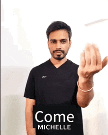 a man with a beard is wearing a black shirt and giving a middle finger .