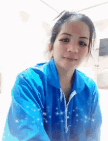 a woman is wearing a blue jacket and smiling .