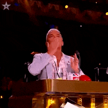 a man stands at a podium with his arms outstretched in front of a star