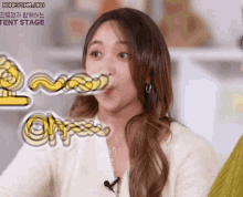 a woman is making a funny face while wearing a white sweater and a microphone .