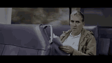 a man is sitting on a train holding a piece of paper .
