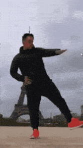 a man is standing on one leg in front of the eiffel tower .