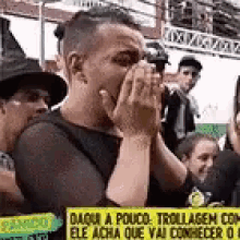 a man in a witch hat is covering his mouth with his hands while standing in front of a crowd of people .