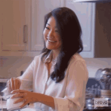 a woman in a white shirt is smiling in a kitchen with bravo written on the bottom