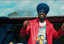a man wearing sunglasses and a red jacket has a t-shirt that says ' reggae ' on it
