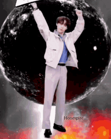 a man in a white jacket and pants stands in front of a black sphere with the word hone spire on the bottom