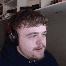 a man with a beard wearing headphones and a blue sweatshirt