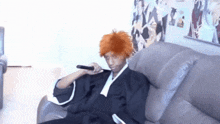 a man in a bleach costume is sitting on a couch holding a microphone