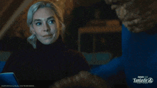 a woman looks at a man in a blue shirt that says fantastic four
