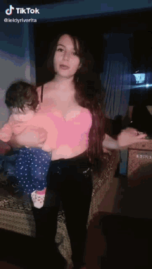 a woman in a pink top is holding a baby in her arms and the caption reads tiktok