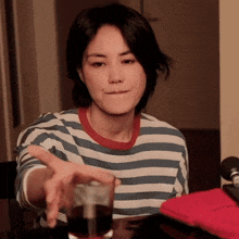 a woman in a striped shirt reaches for a glass
