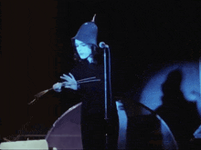 a woman singing into a microphone wearing a blue hat