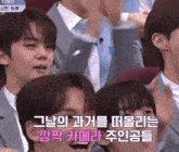 a group of young men are sitting in a row and one of them is wearing a gray suit