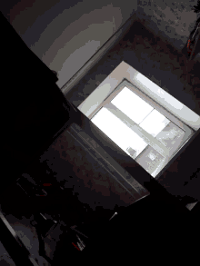a dark room with a window and a few pieces of furniture