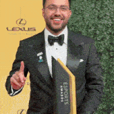 a man in a tuxedo is holding a trophy for the lexus esports awards