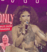 a woman is singing into a microphone in front of a sign that says " only "