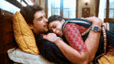 a man and a woman are laying on a bed hugging