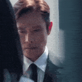 a man in a suit and tie is looking at another man .