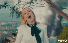 a woman is singing in front of a tree and the word vevo is below her