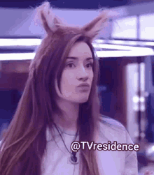 a woman with bunny ears on her head is making a face .