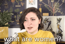 a woman in a yellow sweater is talking into a microphone while asking what are women