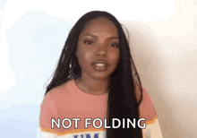 a woman with long black hair is standing in front of a white wall and says `` not folding '' .
