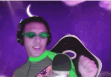 a man wearing headphones and sunglasses is dancing in front of a microphone .