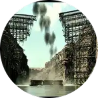 a picture of a bridge with smoke coming out of it and mountains in the background