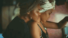 two women are hugging each other in a car . one of the women is wearing a head scarf .