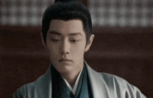 a close up of a man wearing a kimono and looking down .