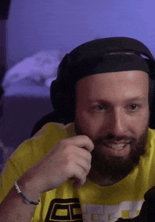 a man with a beard is wearing headphones and a yellow shirt with the letter e on the front