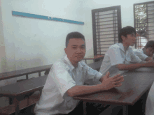a young man sits at a desk with a sticker on his shirt that says ' a ' on it