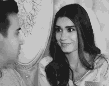 a man and a woman are looking at each other and smiling