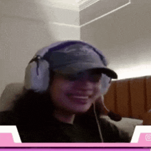 a woman wearing headphones and a baseball cap is smiling