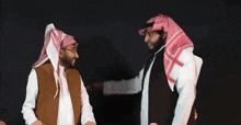 two men wearing head scarves are standing next to each other and one is giving the other a high five
