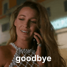 a woman wearing a pearl necklace says goodbye while talking on a cell phone